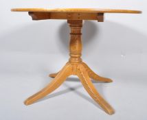A contemporary round elm dining table, raised on a turned column and four splayed legs,