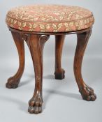 A Victorian oak stool, the circular over-stuffed seat above four cabriole supports with claw feet,