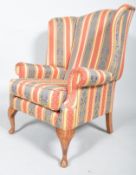 A 20th century Queen Anne style upholstered wing back armchair with barrel rolled arms,