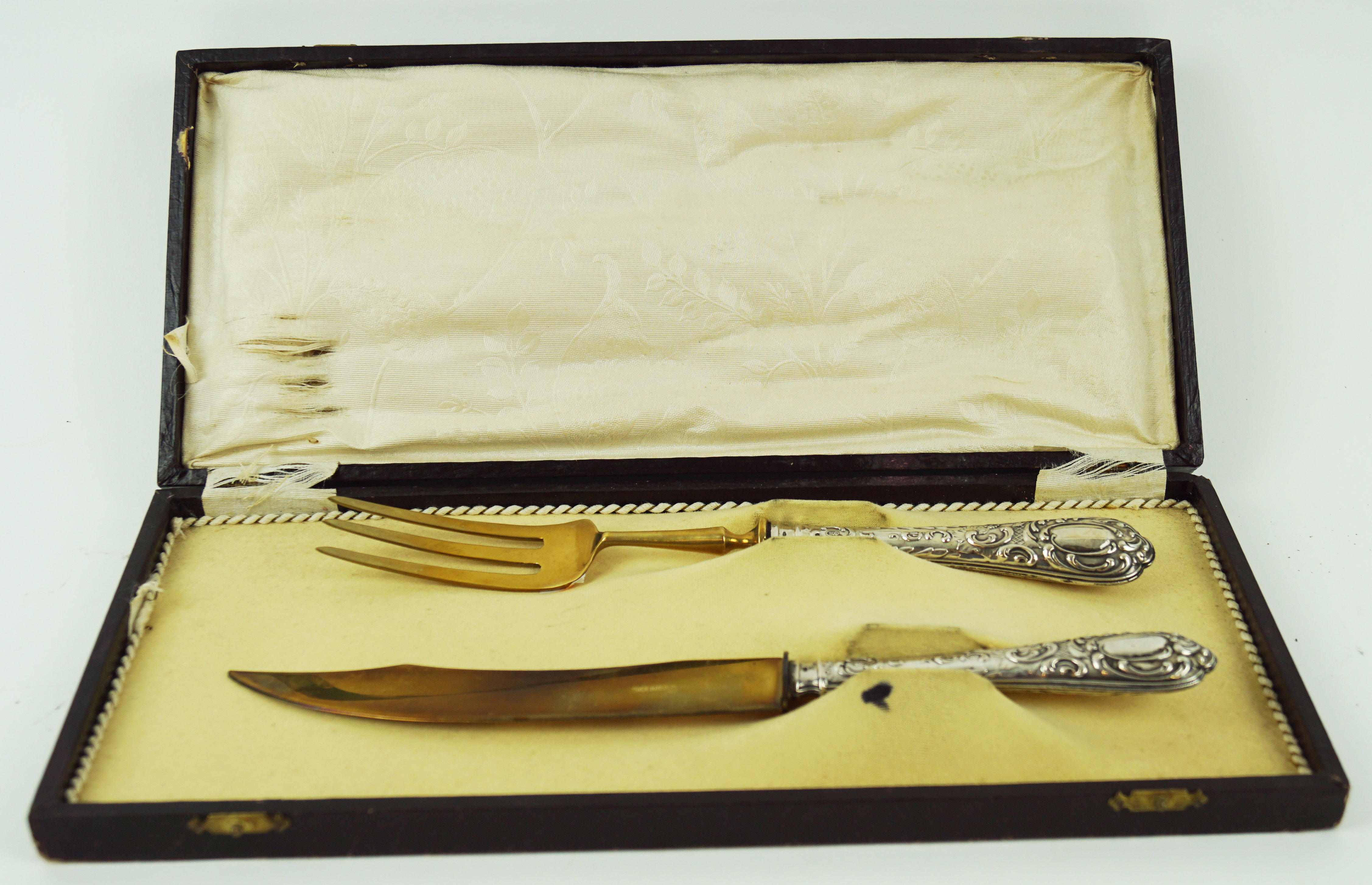 A Solingen gilded serving knife and fork, with embossed white metal handle,