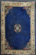 A modern Chinese blue ground wool carpet with central pink flower & calligraphic medallion,