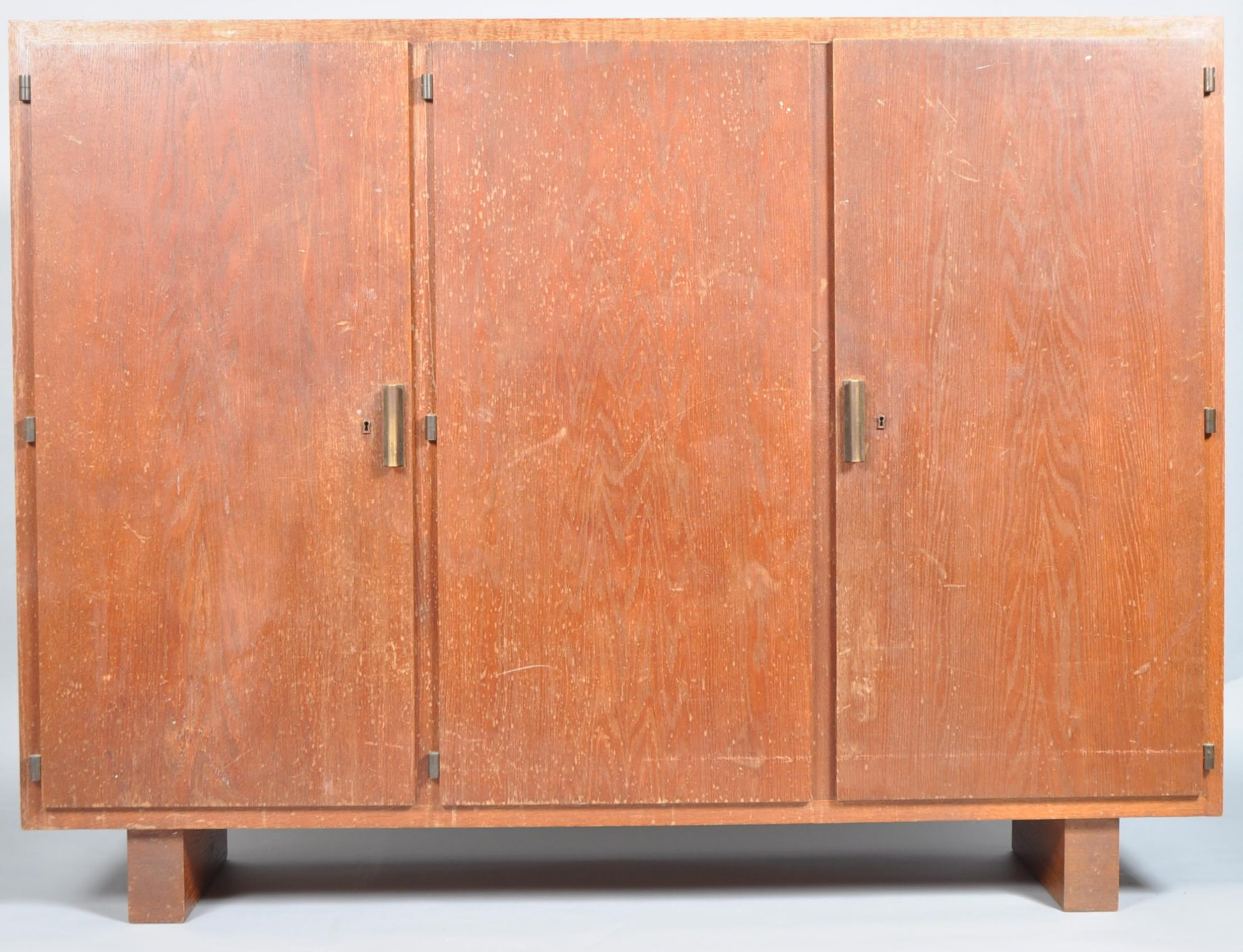 A 1930's Art Deco oak three door cupboard having bronze handles,