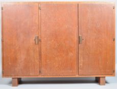 A 1930's Art Deco oak three door cupboard having bronze handles,