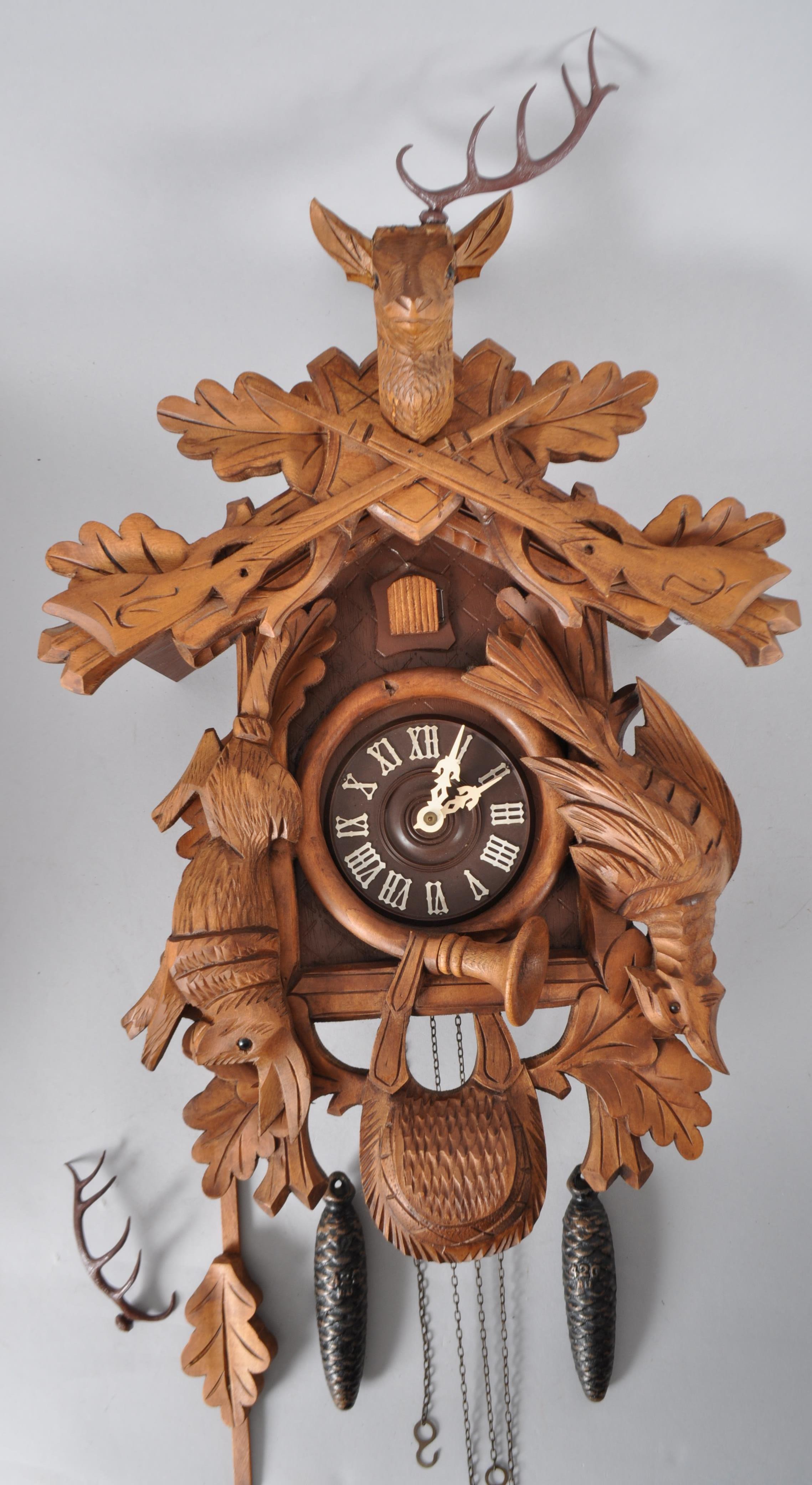 A German carved wooden Cuckoo clock, surmounted with a stag,