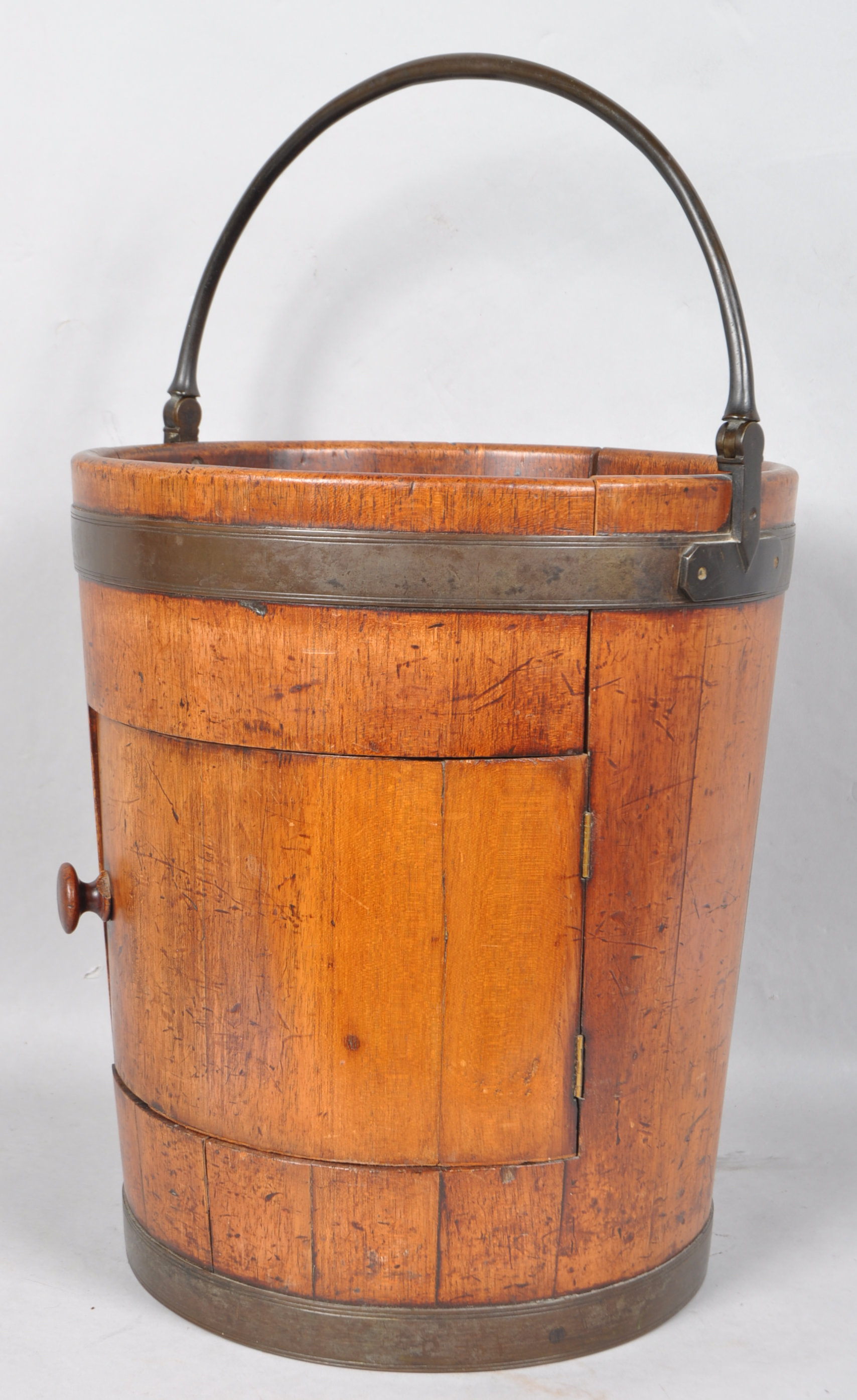 An early 19th century mahogany pot cupboard in the form of a large brass bound coopered peat bucket,