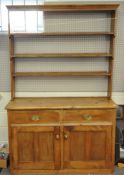 A pine Welsh dresser with raised back above two short drawers above two cupboard doors