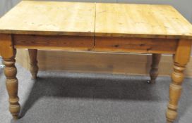 A pine kitchen table with single drawer raised on baluster legs