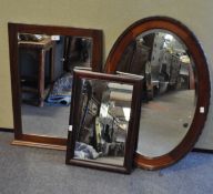 A mahogany framed oval wall mirror and two other wall mirrors