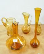 A collection of amber gold glass jugs together with a tall bud vase