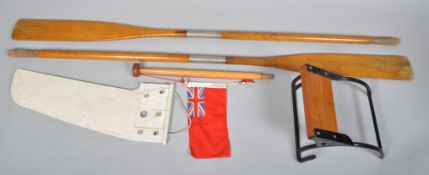 Two oars and a rudder, a red ensign and a cox's seat.