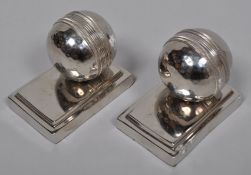 A pair of novelty silver metal cricket ball bookends,