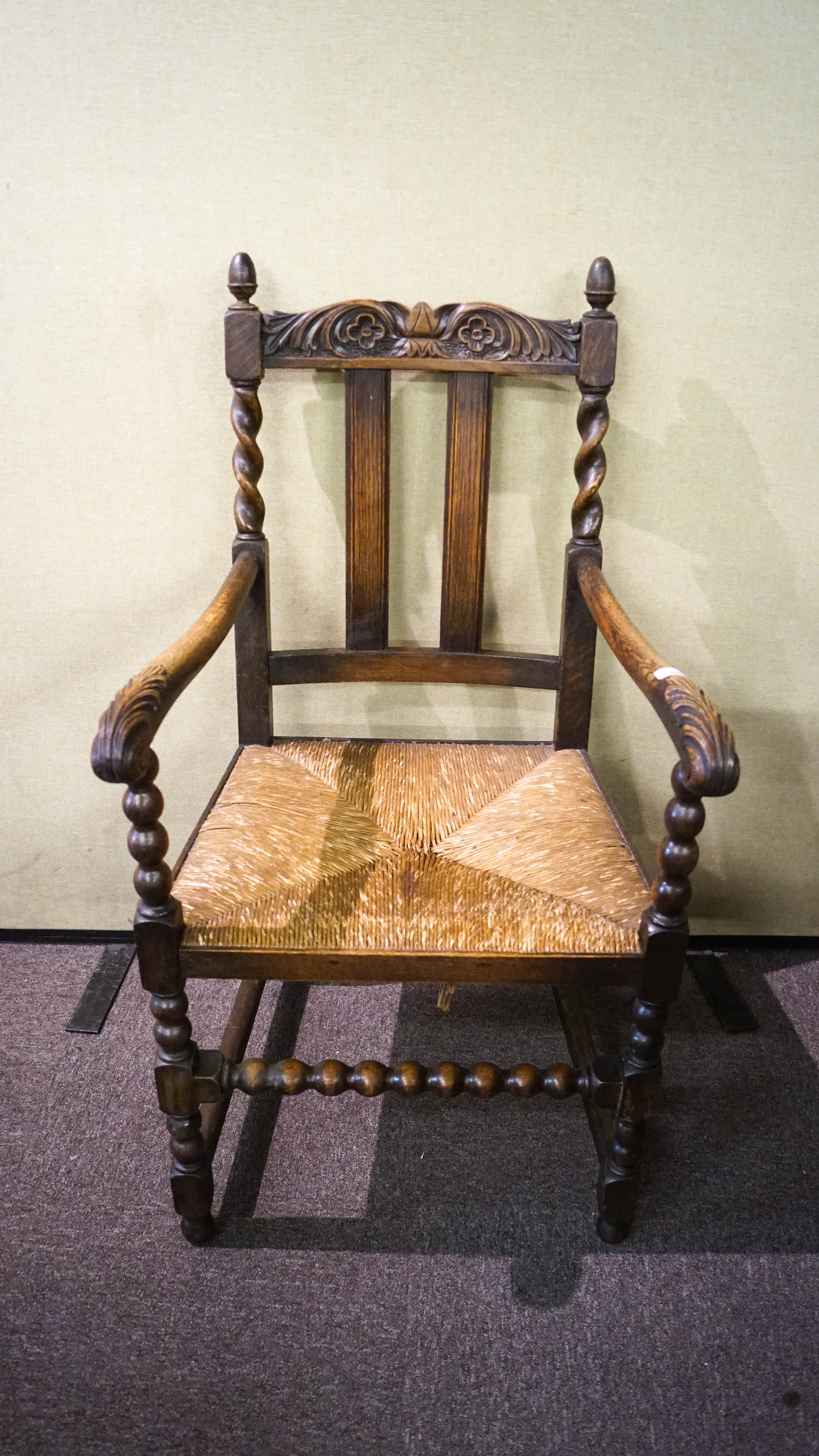 A carved oak elbow chair with rush seat
