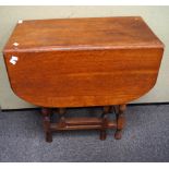 A 1930's vintage oak drop leaf and gate leg table raised on turned legs.