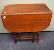 A 1930's vintage oak drop leaf and gate leg table raised on turned legs.