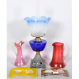 An oil lamp, two cranberry glass jugs and two glass sanitiser dispenser stands