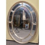 A contemporary oval silvered mirror having an eight panel border. Measures; 112cm x 83cm.