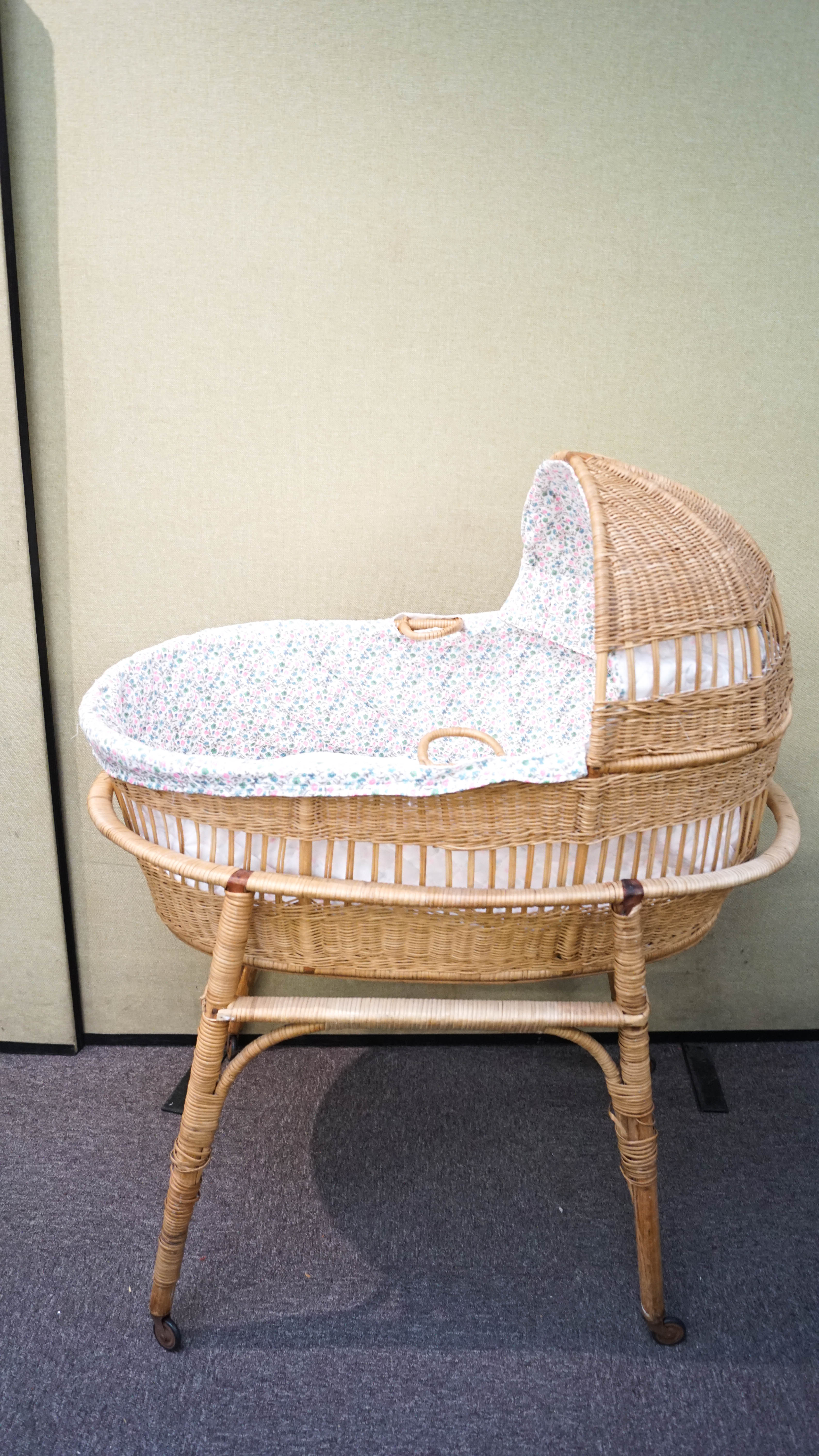 A 1960's retro vintage wicker weaved childs cradle on stand and castors.