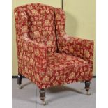 A 19th Century Victorian wingback armchair having floral upholstery and raised on turned legs and