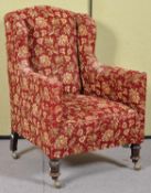 A 19th Century Victorian wingback armchair having floral upholstery and raised on turned legs and