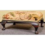 A mahogany footstool with floral style upholstery. Measures; 27cm x 60cm x 44cm.