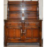 A 20th Century Ercol colonial dresser having plate rack top above cupboard.