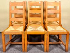 A set of six contemporary oak ladderback dining chairs with rush drop in seats.