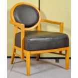 A contemporary Art Deco inspired oak lounge chair upholstered in faux leather. Measures; 86cm high.