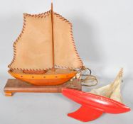 An early 20th century wooden sailing boat lamp and a red painted wooden pond sailing boat
