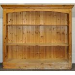 A pine bookcase having a flared top, two shelves and raised on a plinth base.