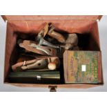 A vintage safe box tin trunk containing a collection of planes and other tools.