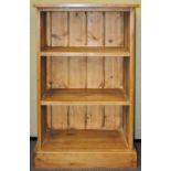 A 20th Century pine bookshelf having a flared top, two shelves and raised on a plinth base.