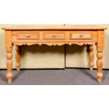 A large 20th Century pine console table having three frieze drawers, all raised on turned legs.