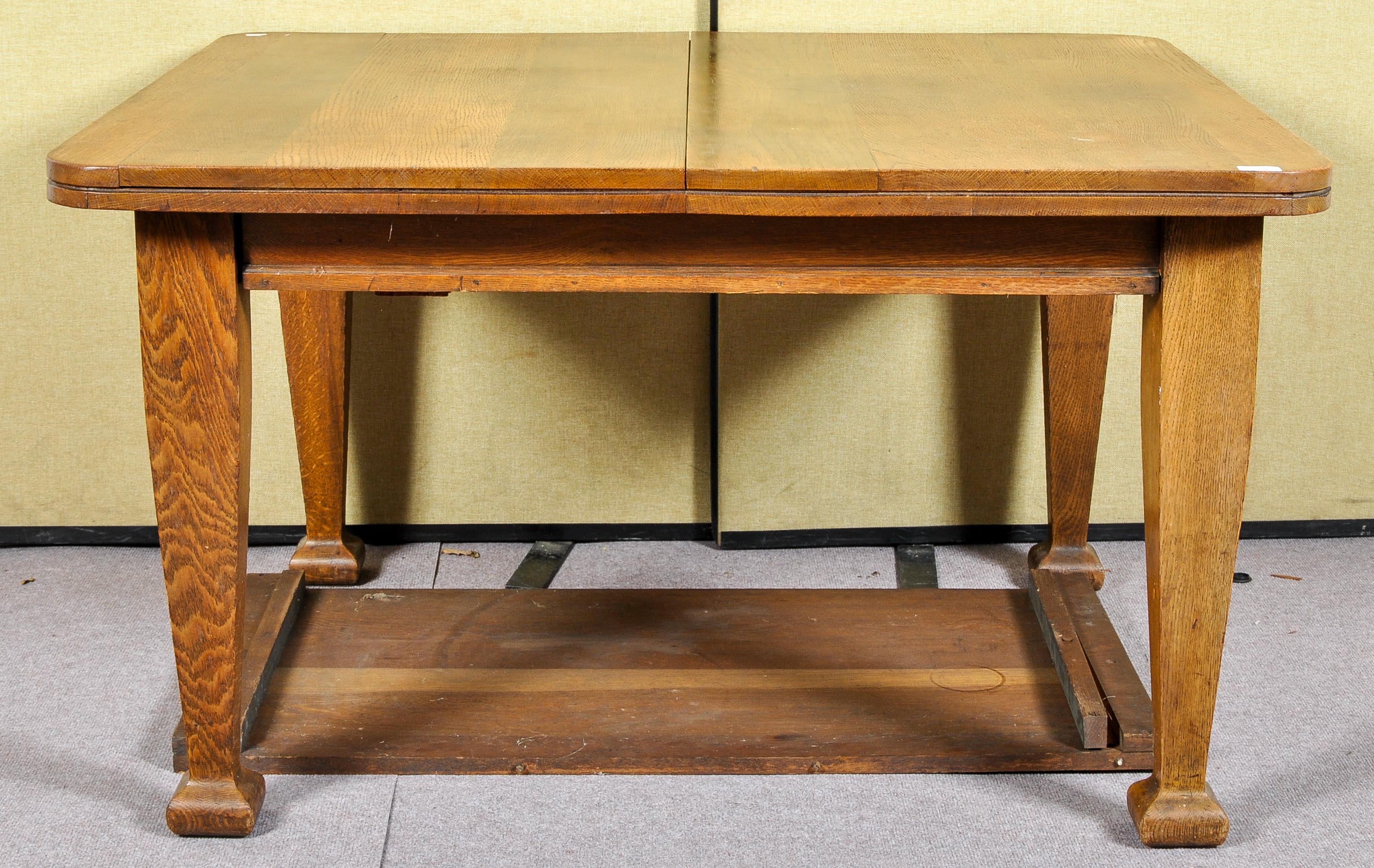 A 19th/20th Century arts and crafts oak winding extending table raised on squared shaped legs.