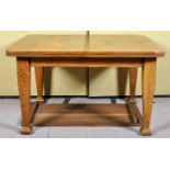 A 19th/20th Century arts and crafts oak winding extending table raised on squared shaped legs.