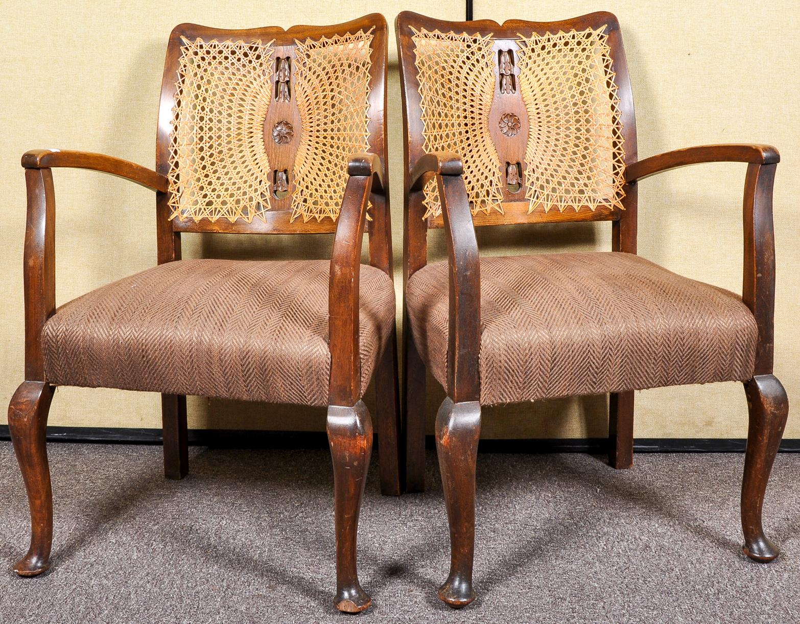 A pair of Edwardian oak open armchairs having bergere cane work back rest and deep cushioned seat,