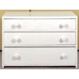 A white painted chest of drawers having three straight drawers.