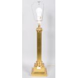 A large brass Corinthian column electric lamp base with harp raised on squared flared base.