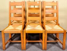 A set of six contemporary oak ladderback dining chairs with rush drop in seats, 106cm high.