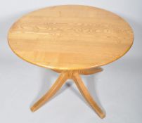 A contemporary round elm dining table, raised on a turned column and four splayed legs,
