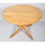 A contemporary round elm dining table, raised on a turned column and four splayed legs,