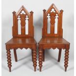 A pair of Victorian Gothic hall chairs, mid 19th century, with pierced arched high backs,
