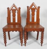 A pair of Victorian Gothic hall chairs, mid 19th century, with pierced arched high backs,