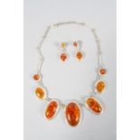 A costume jewellery necklace and earrings with cabochon orange stones in the style of Amber.