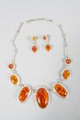 A costume jewellery necklace and earrings with cabochon orange stones in the style of Amber.