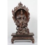 A Chinese carved hardwood sculpture of a Bodhisattva in a lotus recess on rockwork on a rectangular
