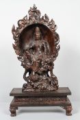 A Chinese carved hardwood sculpture of a Bodhisattva in a lotus recess on rockwork on a rectangular