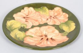 A Moorcroft 'Peach Hibiscus' pattern circular dish on a green ground,