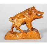 A carved wood vintage sculpture of a boar, naturalistically modelled on a rocky ground,