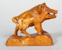 A carved wood vintage sculpture of a boar, naturalistically modelled on a rocky ground,