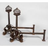 A large pair of steel fire dogs, with pierced spiral ball finials,